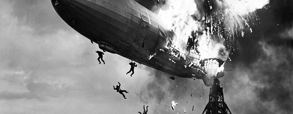 Hindenburg airship bursting into flames with people jumping and running below
