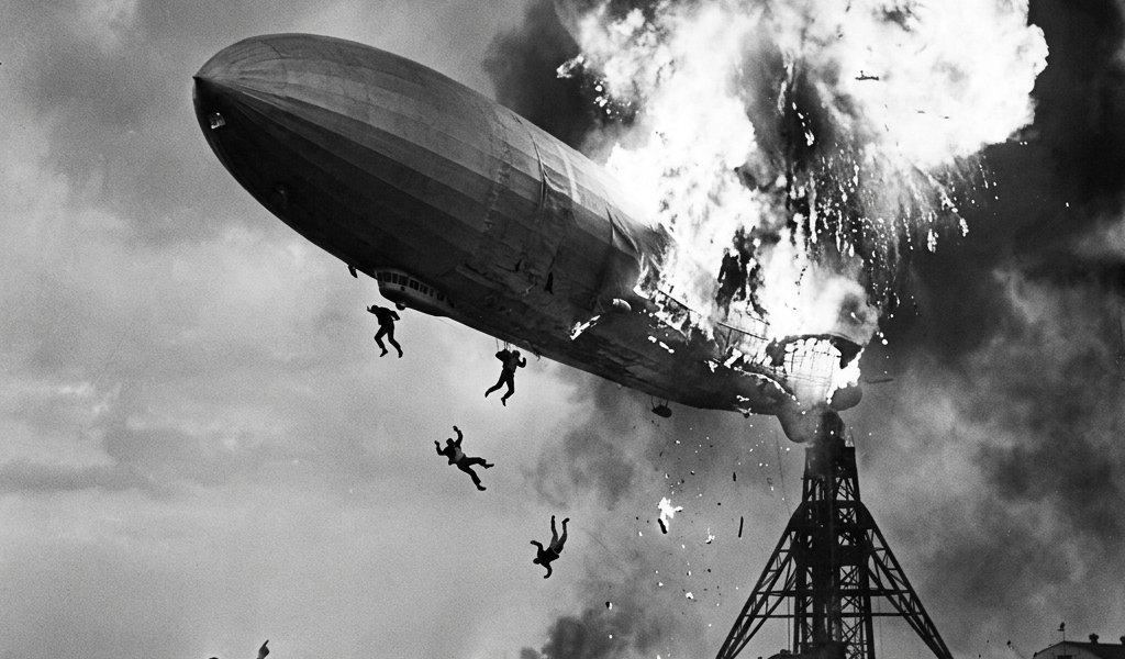 Hindenburg airship bursting into flames with people jumping and running below